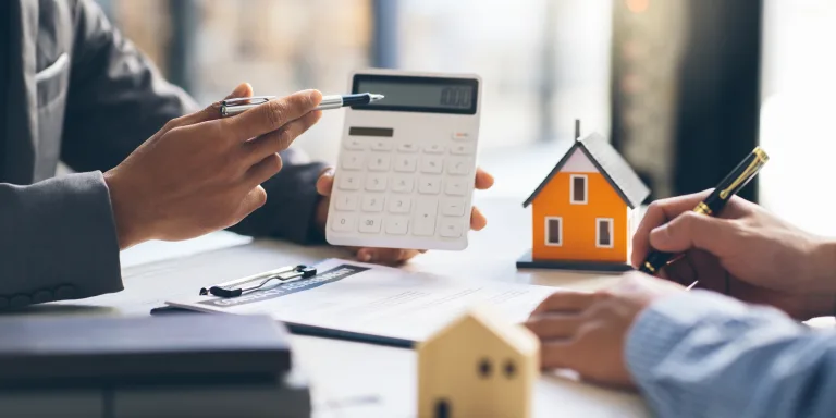 Hausmodell mit Makler und Kunde, die über einen Kauf-, Versicherungs- oder Darlehensvertrag für Immobilien oder Grundstücke sprechen