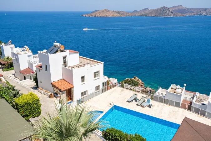 Weiße Ferienhäuser in der Ferienanlage mit Meerblick, Schwimmbad und Palmen