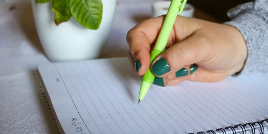 Frau hält Stift in der Hand über einem Block um einen Überblick über ihr Geld zu gewinnen
